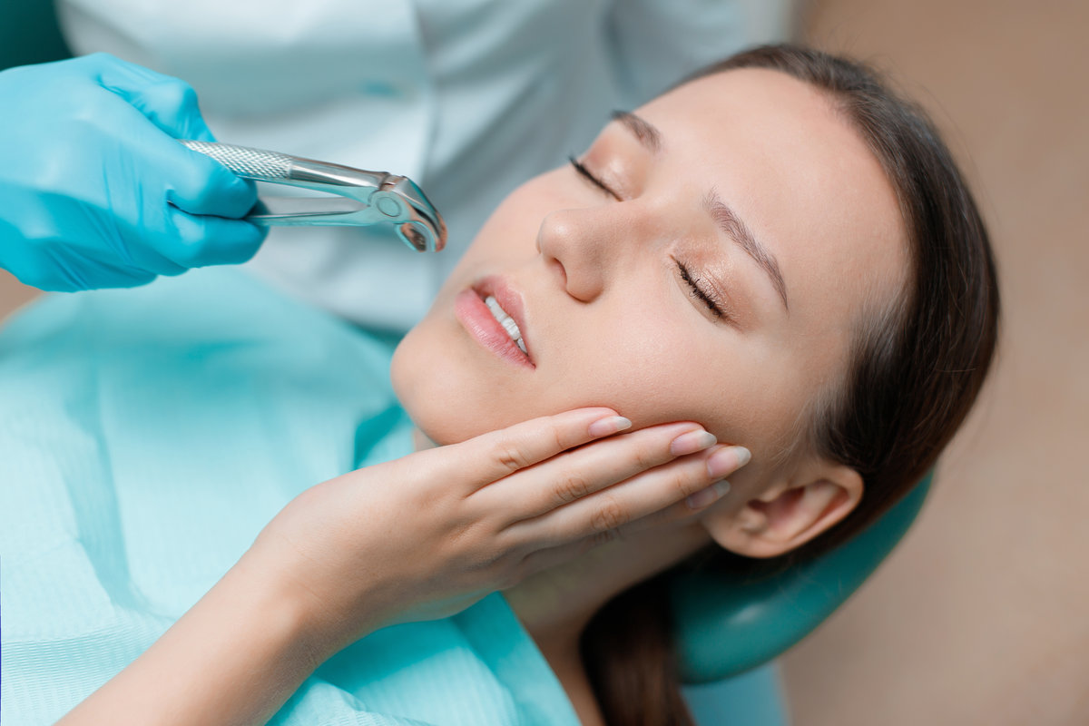 Patient in dental chair. Dentist's hands with blue gloves work with a dental tools. Beautiful young woman having dental treatment at dentist's office.