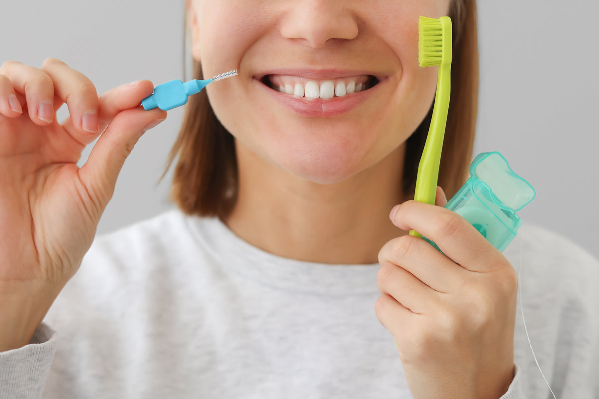 Unrecognisable woman with white teeth holds dental floss, toothbrush and interdental brush to for prevent oral disease. Health care dentistry and oral hygiene concept.Daily routines caries prevention.