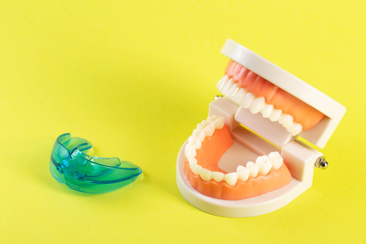Therapeutic mouthguard on the background of a dental jaw mockup on a yellow background. Treatment of teeth grinding, bruxism in children and adults. Protecting tooth enamel from abrasion when grinding teeth, close-up, Copy space for text